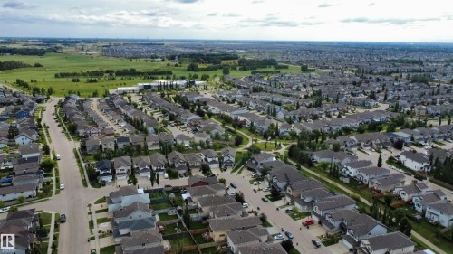 Aerial perspective showcasing a residential neighborhood with numerous single-family homes, paved streets, and a backdrop of open green fields - 1216 37C Avenue Nw, Edmonton, AB - Outdoor With View