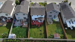 Rear exterior with a red-stained deck, a detached shed, and a fenced backyard - 