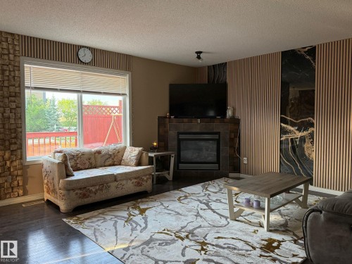 Living area with dark wood-finish flooring and a large window - 1216 37C Avenue Nw, Edmonton, AB - Indoor Photo Showing Living Room With Fireplace