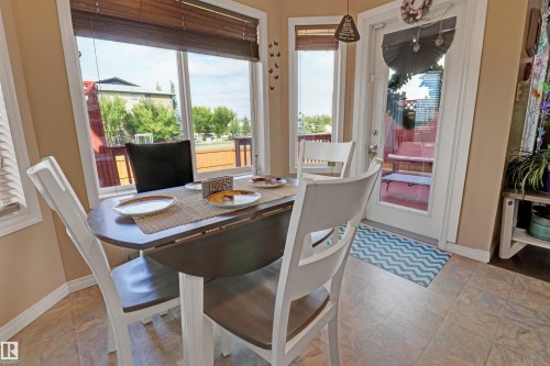 Bay window dining area featuring multiple windows with wood-tone blinds, a glass-paneled door, and tile flooring - 1216 37C Avenue Nw, Edmonton, AB - Indoor Photo Showing Dining Room
