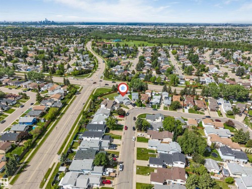 Aerial perspective showcasing a residential neighborhood with tree-lined streets and a distant city skyline - 3332 43 Street, Edmonton, AB 