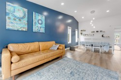 Open-concept living and dining area featuring vaulted ceilings, recessed lighting, and wood-finish flooring - 