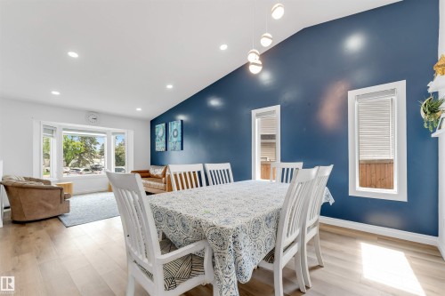Vaulted ceiling with recessed lighting, light wood-finish flooring, and a dining area featuring a prominent blue accent wall - 3332 43 Street, Edmonton, AB 