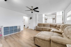 Open-concept living space featuring wood-finish flooring, a ceiling fan, and white painted walls - 