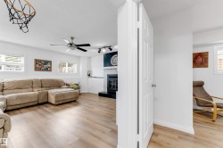 Spacious interior featuring wood-finish flooring, white walls, and multiple windows with white blinds - 