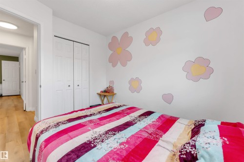 Bedroom featuring wood-finish flooring, white walls, and bi-fold closet doors - 3332 43 Street, Edmonton, AB 