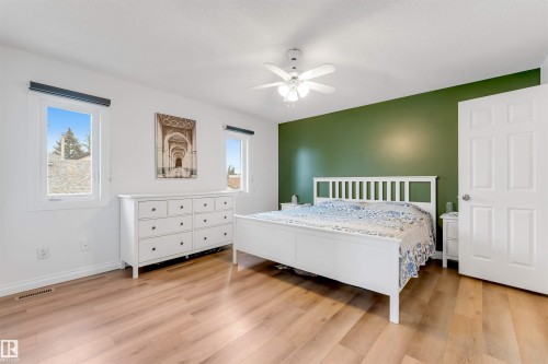 Bedroom featuring light wood-finish flooring, white walls, and a prominent green accent wall - 3332 43 Street, Edmonton, AB 