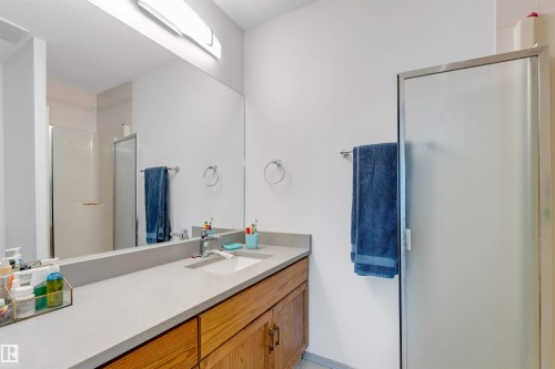 Bathroom featuring an elongated vanity with a light-toned countertop, wood-finish cabinetry, and an integrated sink - 3332 43 Street, Edmonton, AB 