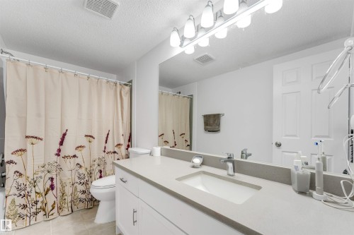 Bathroom featuring a white vanity with an integrated sink, a light gray countertop, and a large mirror - 3332 43 Street, Edmonton, AB 