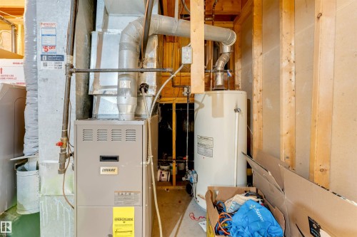 Utility area featuring a furnace and a water heater, with exposed timber framing and concrete block walls - 3332 43 Street, Edmonton, AB 