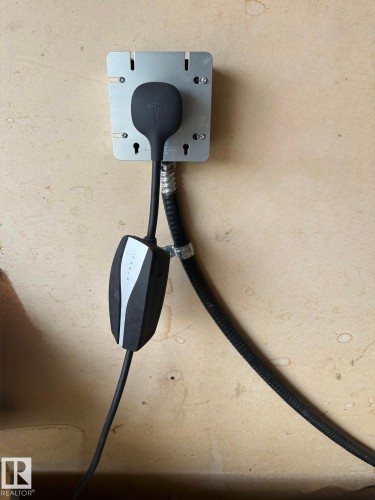 Electric vehicle charging station featuring a wall-mounted bracket and integrated cable management - 3332 43 Street, Edmonton, AB 