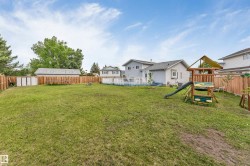Expansive backyard featuring a manicured lawn, full wood fencing, and a multi-level deck off the residence - 