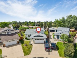 Split-level residence featuring a gray shingle roof, attached garage, and paved driveway - 