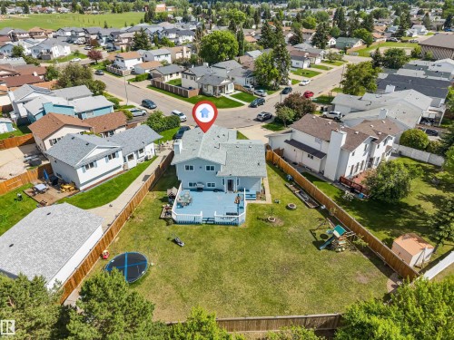Expansive backyard featuring a large elevated deck with white railings, a manicured lawn, and perimeter fencing - 3332 43 Street, Edmonton, AB 