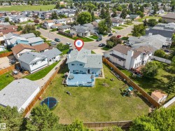 Expansive backyard featuring a large elevated deck with white railings, a manicured lawn, and perimeter fencing - 