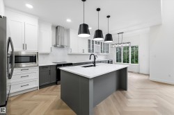 Modern kitchen featuring a large central island with a solid surface countertop and matte black fixtures - 