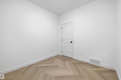 Herringbone pattern wood-finish flooring with crisp white baseboards and walls - 