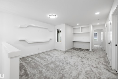 Carpeted room with a built-in desk and shelving - 917 Elderberry Landing, Edmonton, AB 