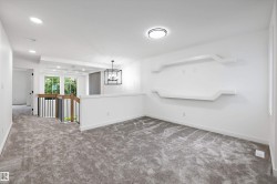 Carpeted loft space featuring built-in display shelving, a contemporary chandelier, recessed lighting, and white trim throughout - 