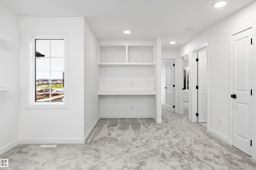 Bright room with built-in desk and shelving, recessed lighting, and light gray patterned carpeting - 917 Elderberry Landing, Edmonton, AB 