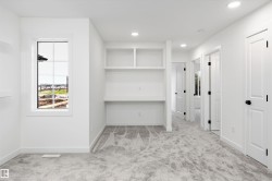 Bright room with built-in desk and shelving, recessed lighting, and light gray patterned carpeting - 