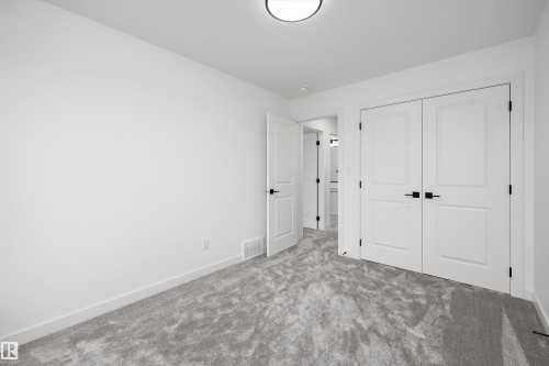 Room featuring light gray patterned carpeting, white painted walls, and white trim - 917 Elderberry Landing, Edmonton, AB 