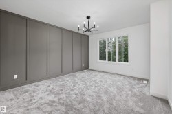 Room featuring a dark gray accent wall with vertical paneling, light gray carpeting, and a modern black chandelier - 