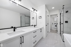 Double vanity featuring white cabinetry, quartz countertops, and matte black fixtures - 