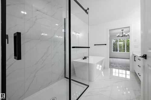 Contemporary bathroom featuring a spacious glass-enclosed shower with black trim, a standalone soaking tub, and marble-look tile flooring - 917 Elderberry Landing, Edmonton, AB 