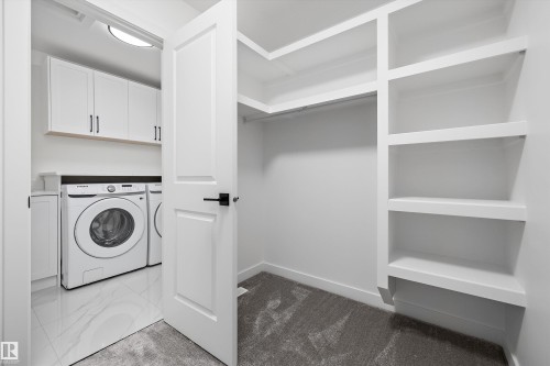 Dedicated laundry area with white cabinetry and a built-in countertop - 917 Elderberry Landing, Edmonton, AB 