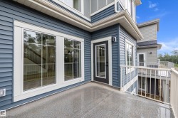 Private outdoor balcony featuring a textured concrete surface, white metal railing, and blue horizontal siding - 
