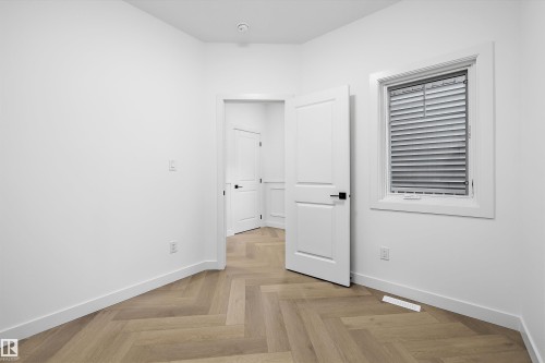 Interior room featuring herringbone wood-finish flooring, white baseboards, and a white interior door with black hardware - 917 Elderberry Landing, Edmonton, AB 