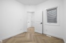 Interior room featuring herringbone wood-finish flooring, white baseboards, and a white interior door with black hardware - 917 Elderberry Landing, Edmonton, AB 