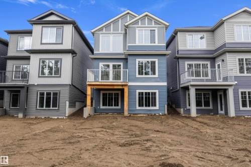 Contemporary multi-level exterior featuring blue and gray siding, multiple windows, and a second-story balcony with white railings - 917 Elderberry Landing, Edmonton, AB 