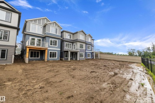 Contemporary multi-level property featuring blue and gray siding, multiple gables, white-framed windows, and a private balcony with white railings - 917 Elderberry Landing, Edmonton, AB 