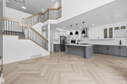 Open-concept kitchen featuring an oversized island, two-tone cabinetry, and stainless steel appliances - 