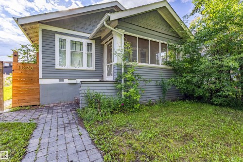 Craftsman-style exterior featuring gray horizontal siding, white trim, a screened-in porch, and a paved walkway - 11238 123 Street, Edmonton, AB 