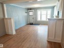 Spacious entry area with wood-finish flooring, white baseboards, and light blue walls - 11238 123 Street, Edmonton, AB 