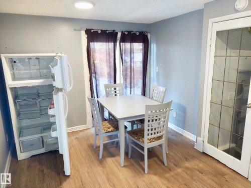 Dining area featuring wood-finish flooring, light grey painted walls, and a white interior door with glass panes - 11238 123 Street, Edmonton, AB 