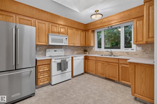 Kitchen featuring wood cabinetry, light-toned countertops, a full suite of appliances, and tile flooring - 17603 85 Avenue Nw, Edmonton, AB 