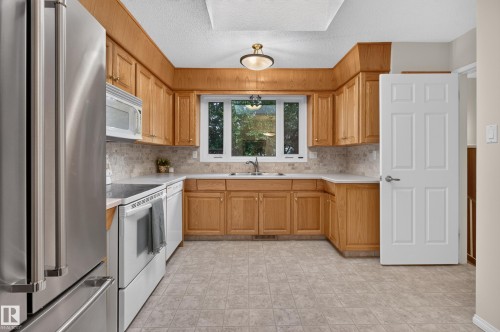 Kitchen featuring wood cabinetry, light-toned countertops, and a tiled backsplash - 17603 85 Avenue Nw, Edmonton, AB 