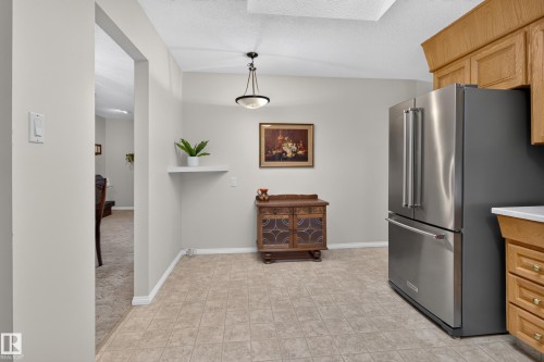 Spacious kitchen area featuring tile flooring, stainless steel refrigerator, and wood-finish cabinetry - 17603 85 Avenue Nw, Edmonton, AB 
