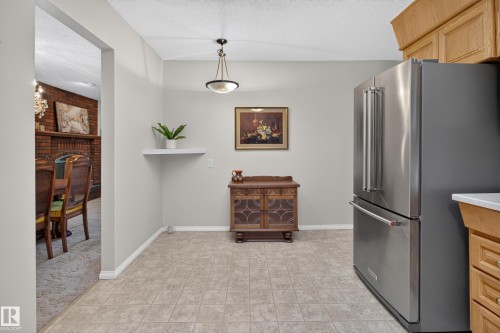 Kitchen area featuring a stainless steel refrigerator, light-toned cabinetry, and a drop pendant light fixture - 17603 85 Avenue Nw, Edmonton, AB 