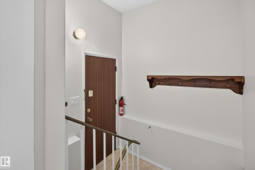 Entryway featuring a wood-grain door with brass hardware, wall-mounted light fixture, and a built-in wooden coat rack - 17603 85 Avenue Nw, Edmonton, AB 
