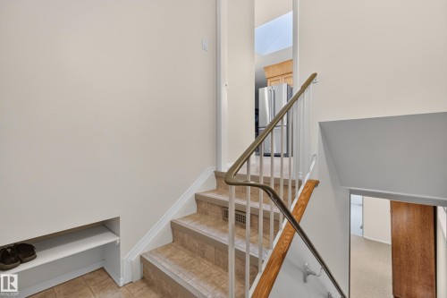 Staircase with tile steps, white risers, and a metal and wood handrail - 17603 85 Avenue Nw, Edmonton, AB 