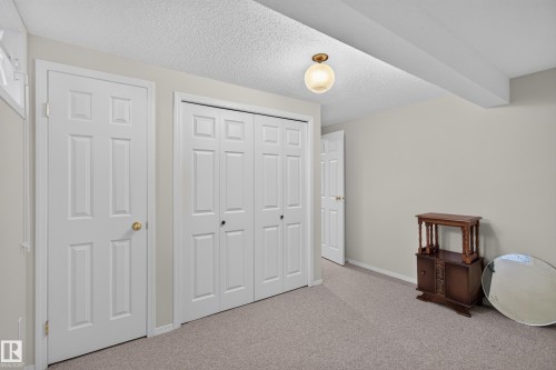 Neutral-toned carpeted room featuring a ceiling-mounted light fixture, white six-panel doors, and a bi-fold closet - 17603 85 Avenue Nw, Edmonton, AB 