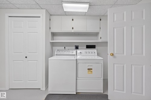 Dedicated laundry area featuring white cabinetry, shelving, and a drop ceiling - 17603 85 Avenue Nw, Edmonton, AB 