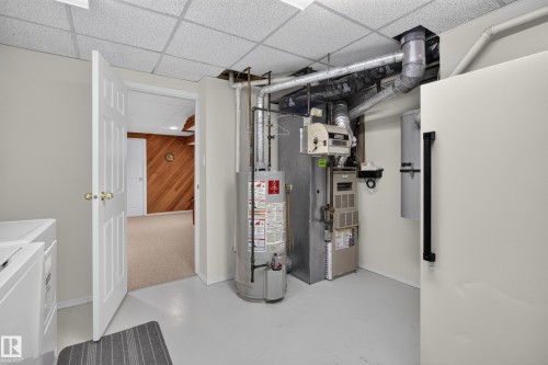 Utility room featuring a drop ceiling, painted concrete flooring, and exposed ductwork - 17603 85 Avenue Nw, Edmonton, AB 