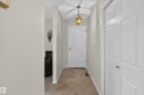 Entryway featuring a paneled door with brass hardware, a brass chandelier, and white baseboards - 17603 85 Avenue Nw, Edmonton, AB 