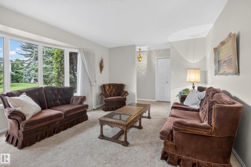 Living space featuring expansive bay windows, light-toned carpeting, and a white paneled door - 17603 85 Avenue Nw, Edmonton, AB 